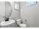 Clean and modern half-bathroom with a pedestal sink, toilet, and decorative artwork at 6513 Dry Fork Cir, Frederick, CO 80516