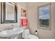 Powder room with pedestal sink, toilet, decorative mirror and light filled window at 861 Circle Rd, Palmer Lake, CO 80133