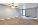 Large bedroom with neutral carpet, a ceiling fan and a large window with light-blocking shade at 6410 S Dayton St # I05, Englewood, CO 80111