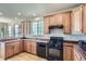 Kitchen with wood cabinets, black appliances, laminate floors, and natural light from the window at 3752 Red Deer Trl, Broomfield, CO 80020