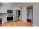 The open-concept kitchen boasts stainless steel appliances, modern cabinetry, and a hardwood floor at 5925 W 86Th Ave, Arvada, CO 80003
