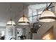 A kitchen island is lit by three pendant lights and looks toward a staircase at 5980 Dunraven Ct, Golden, CO 80403