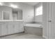 Bright bathroom featuring a tub with tile surround, large mirror, and white vanity at 23895 E Rocky Top Pl, Aurora, CO 80016