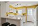 Bright kitchen with yellow accent wall, white cabinetry, modern appliances, and a convenient breakfast bar at 14485 E Hawaii Cir # B, Aurora, CO 80012