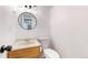 Small half-bathroom featuring wood cabinets, white walls and round mirror at 5421 E Prescott Ave, Castle Rock, CO 80104