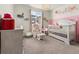 Charming Bedroom with pink accents, a white crib, a glider, and natural light from the window at 28314 E 6Th Pl, Watkins, CO 80137