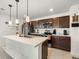 Bright kitchen featuring an island, stainless steel appliances, dark wood cabinets, and modern pendant lights at 28314 E 6Th Pl, Watkins, CO 80137