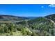 Picturesque aerial view of the property nestled in a lush, mountainous landscape with a distant ocean view at 1295 Hy Vu Dr, Evergreen, CO 80439