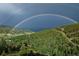 Wide exterior view featuring a vibrant rainbow arcing over a lush, green mountain landscape at 1295 Hy Vu Dr, Evergreen, CO 80439