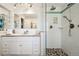 Contemporary bathroom featuring double sinks, sleek fixtures, pebble stone shower, and glass door at 8664 E Monmouth Pl, Denver, CO 80237