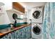 Efficient laundry room with stacked washer and dryer and counter with utility sink at 8664 E Monmouth Pl, Denver, CO 80237