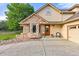 Home exterior featuring stone accents, a custom front door, and a well-manicured yard at 6524 Surry Pl, Parker, CO 80134