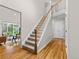 Foyer view of a carpeted staircase with a wooden banister and hardwood floors, leading to the home's upper level at 6524 Surry Pl, Parker, CO 80134