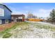Backyard with a covered patio, privacy fence, and grass with scattered snow at 4512 S Yank St, Morrison, CO 80465
