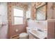 Small bathroom with pink tile, a vanity, and a window at 401 S Oak St, Lakewood, CO 80226