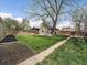 Spacious backyard with lush green grass, wooden fence, a large shade tree and detached garage at 1705 W Stoll Pl, Denver, CO 80221