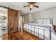 Main bedroom with sliding barn door, wood floors, and a view of the bathroom at 551 E Caley Dr, Centennial, CO 80121