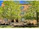 Inviting brick townhome featuring a well-maintained lawn and mature trees providing shade at 7525 E 1St Pl # 1010, Denver, CO 80230