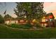 Charming brick home with mature trees, a water feature, and an American flag, creating a welcoming curb appeal at 8662 Kim Ct, Parker, CO 80134