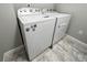 Modern laundry room showcases a white washer and dryer set on tiled flooring at 3074 Distant Rock Ave, Castle Rock, CO 80109