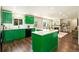 Bright kitchen boasts vibrant green cabinets, stainless appliances, and an island with quartz countertop at 11370 Iola St, Commerce City, CO 80640