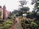 Pathway through a lush garden with mature trees and raised beds at 4425 King St, Denver, CO 80211