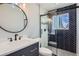 Updated bathroom with a navy vanity, modern fixtures, and a tiled shower with glass doors at 2615 S Laredo Ct, Aurora, CO 80013