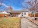 Inviting backyard featuring a covered patio, a deck, and stone walkway surrounded by grass and gravel at 1681 Nome St, Aurora, CO 80010