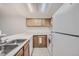 Efficient kitchen with stainless steel sink, wooden cabinetry, and white appliances at 11103 E Alameda Ave # 102, Aurora, CO 80012