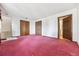 An open-concept living room has pink carpet, a neutral color scheme, and access to the stairs at 11035 E Parker Rd, Parker, CO 80138