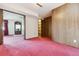 Open living room offering pink carpet, wood paneling, and an access to the front door at 11035 E Parker Rd, Parker, CO 80138