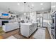 Open-concept living area with a kitchen island, stainless steel appliances, and a fireplace in the background at 5506 Water Avens Dr, Castle Rock, CO 80104