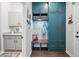 Convenient mudroom with custom teal cabinetry, bench seating, and a view into the adjacent laundry room at 5506 Water Avens Dr, Castle Rock, CO 80104