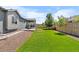 Backyard with green lawn and garden features a stone patio and walkways leading to a fenced perimeter at 15920 Buffalo Run Dr, Commerce City, CO 80022