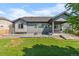 Backyard with green grass, stone patio, fire pit, and exterior of house with covered back porch at 15920 Buffalo Run Dr, Commerce City, CO 80022
