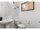 Clean bathroom with a pedestal sink, a toilet and decorative art pieces at 15920 Buffalo Run Dr, Commerce City, CO 80022