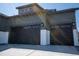 Exterior view of a home with two-car garage doors, stone accents, and modern architectural details at 15920 Buffalo Run Dr, Commerce City, CO 80022