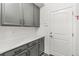 Mud room with gray cabinets, white countertops, and an exterior door at 15920 Buffalo Run Dr, Commerce City, CO 80022