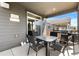 Outdoor patio with gray siding features a glass table with chairs, barbecue grill, and 