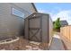 Shed with gray siding has a single door with an 