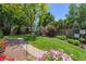 Beautifully landscaped backyard with mature trees, a lush lawn, colorful flowers, and a stone pathway at 3145 Stevens Cir, Erie, CO 80516