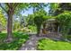 Lush backyard garden with mature trees, a charming pergola and a serene water feature at 3145 Stevens Cir, Erie, CO 80516