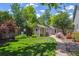 Charming backyard featuring lush green grass, mature trees, and adorable playhouses with a stone pathway at 3145 Stevens Cir, Erie, CO 80516