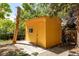 Yellow shed in the backyard with a window, concrete path, and surrounded by trees at 305 Titan St, Aurora, CO 80011