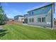 A spacious backyard featuring a lush lawn, a two-story home with blue siding, and a wooden fence at 15378 W 50Th Pl, Golden, CO 80403