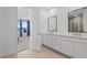 The bathroom features a double vanity, a framed mirror, neutral tile floors, and a view of the adjacent bedroom at 1931 Marlowe W Cir, Erie, CO 80516