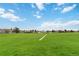 Vast green field stretching towards the horizon under a bright blue sky with scattered clouds at 1768 E Jamison Ave, Centennial, CO 80122