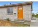 Close up of front entrance featuring light brick, a new orange door and concrete steps at 272 Balsam Ave, Brighton, CO 80601