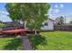 Green backyard featuring a red deck, trees, and well-maintained lawn at 1101 Spruce St, Louisville, CO 80027