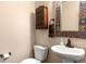 Charming powder room with a decorative mirror, wooden cabinet, and pedestal sink, offering a cozy ambiance at 2276 S Norse St, Lakewood, CO 80228